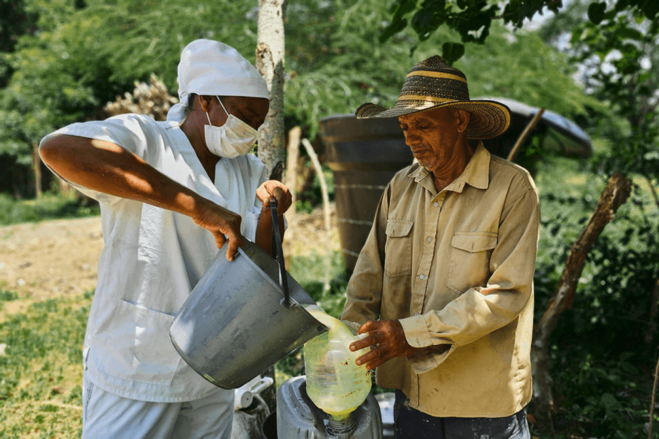 A man pours a liquid into another bucket in an outdoor setting