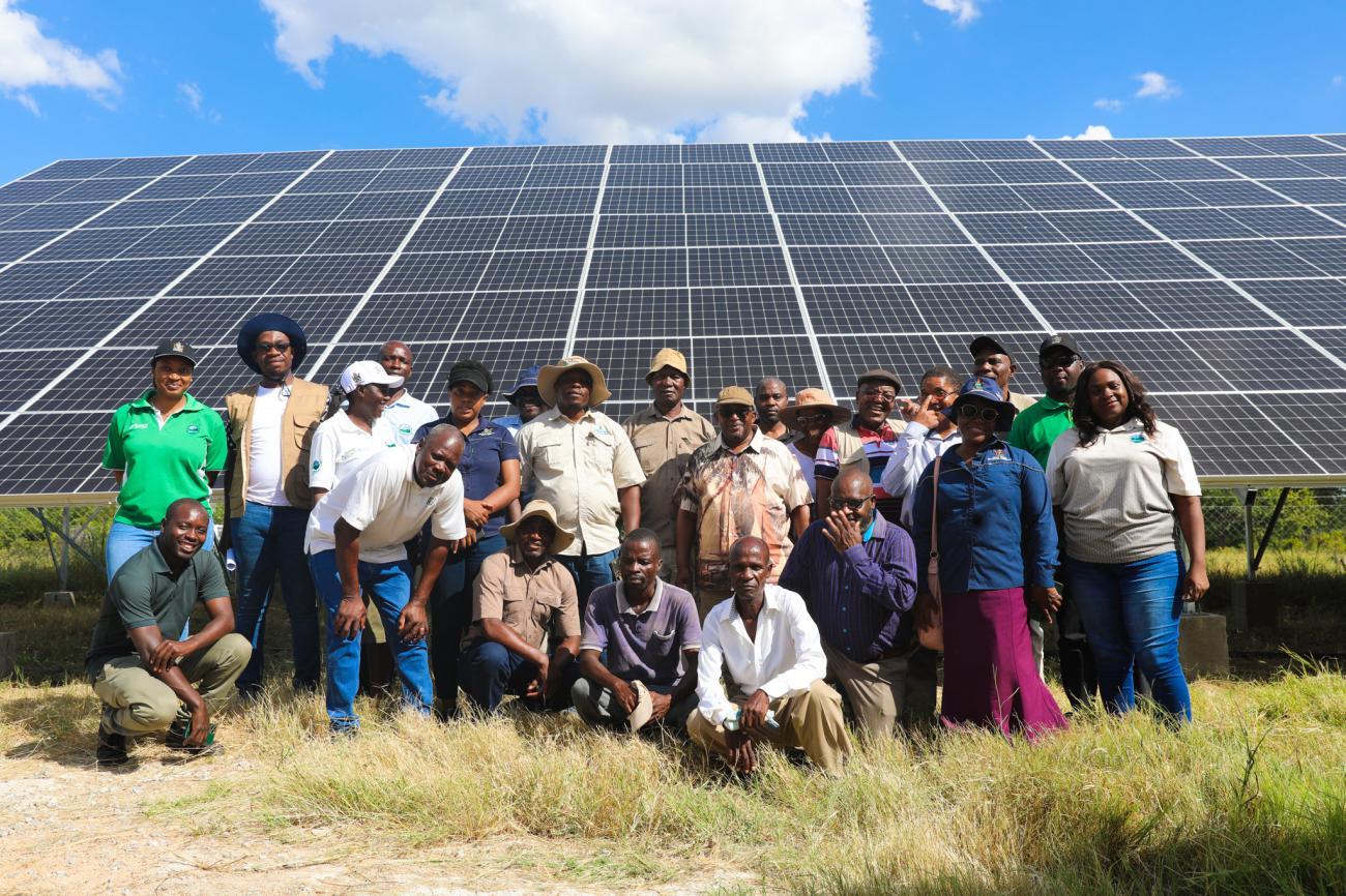 A group of people standing in front of a panel of solar panels
