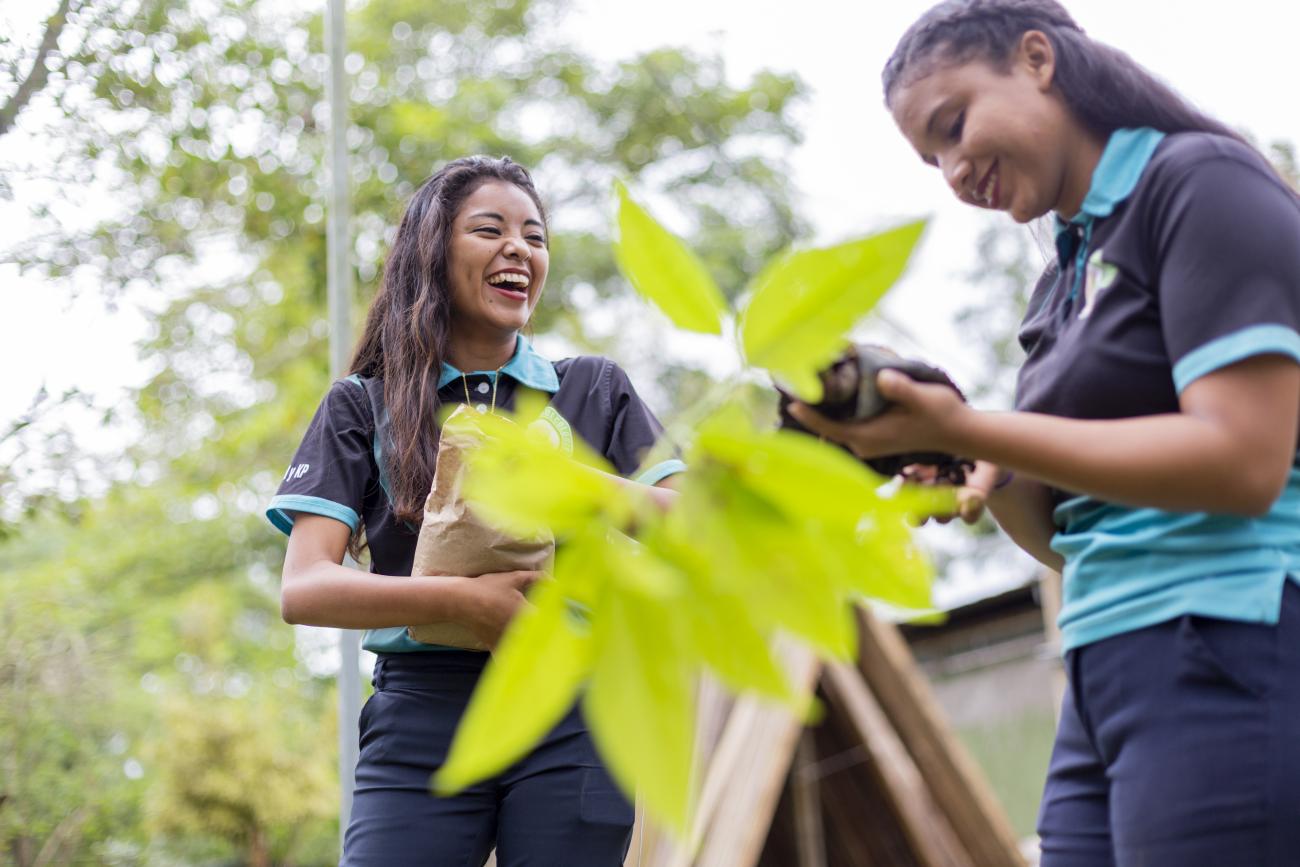 Two girls standing next to green plant
