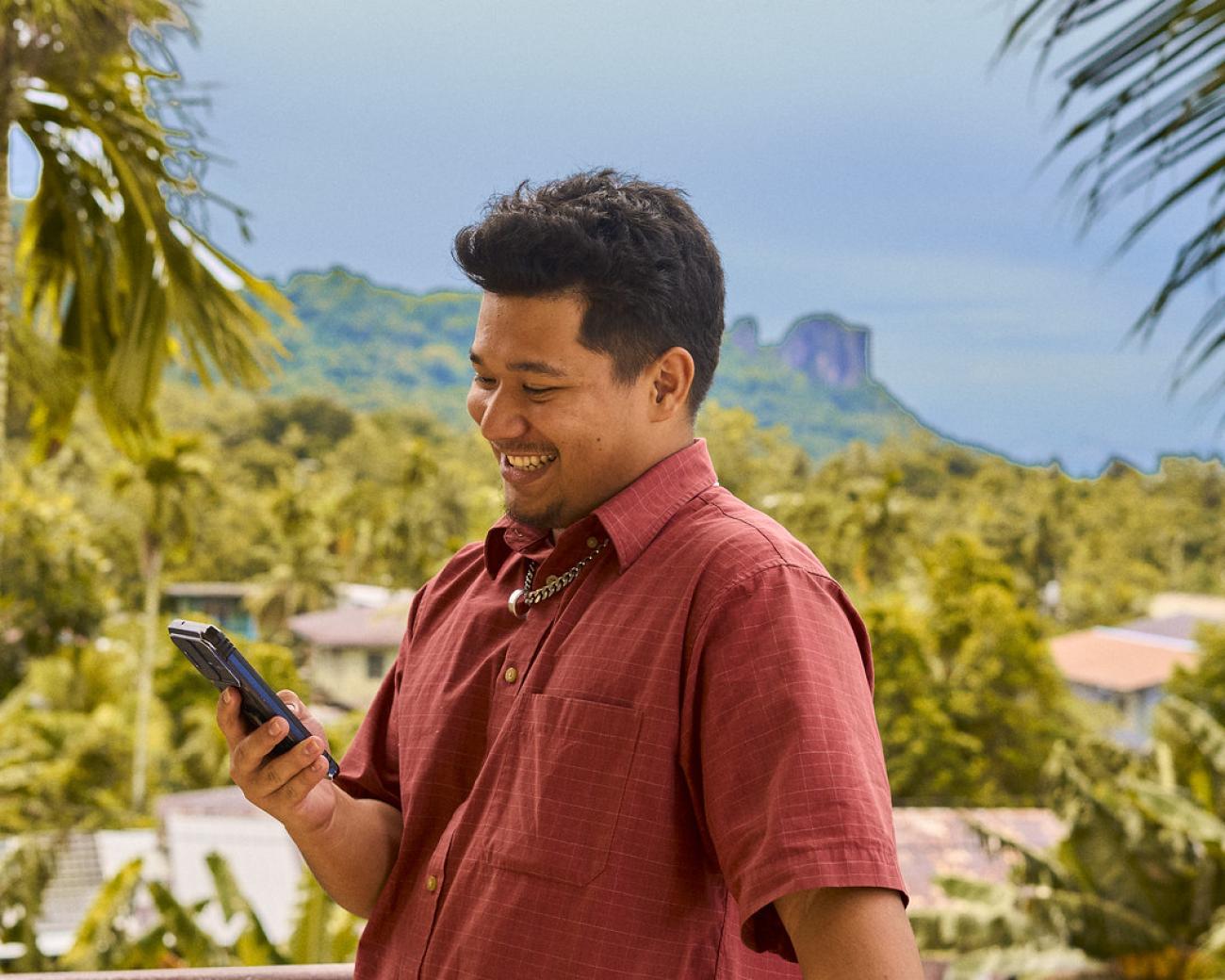 A man in Micronesia happily looks at his cell phone.