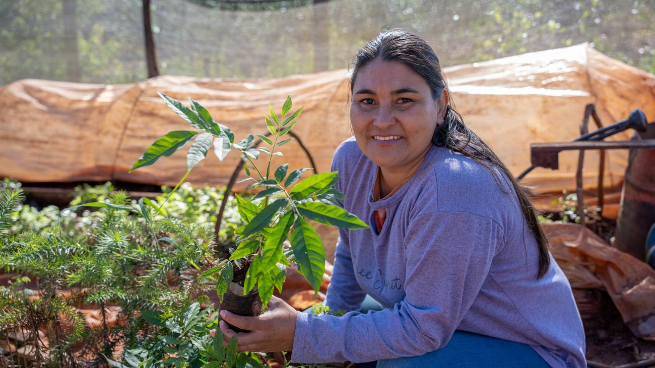 Девушка держит саженец и улыбается