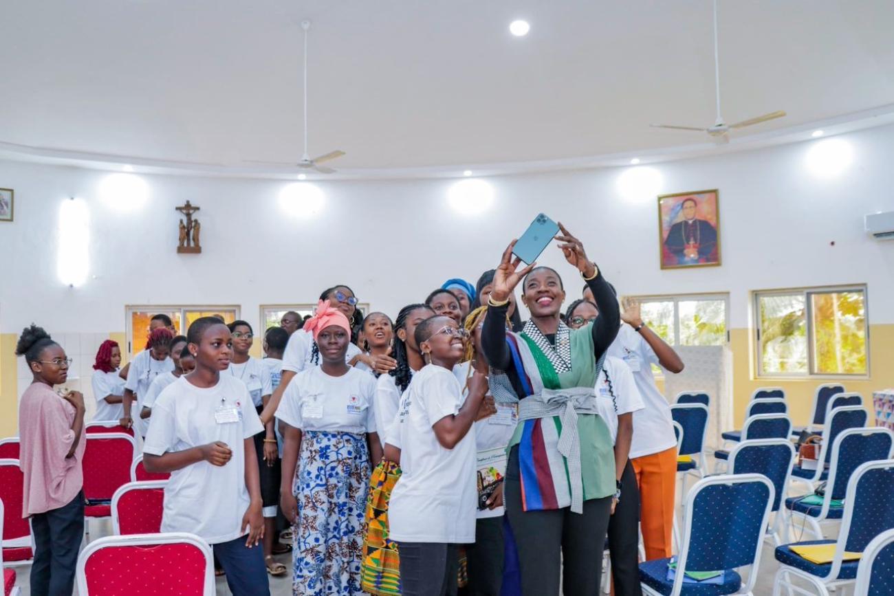 A high-level official in Togo takes a photo with female high school students.
