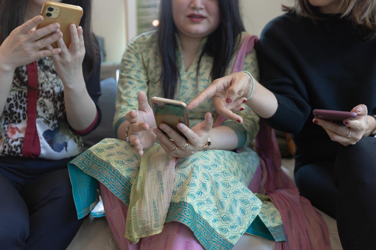 Three women use their smartphones.