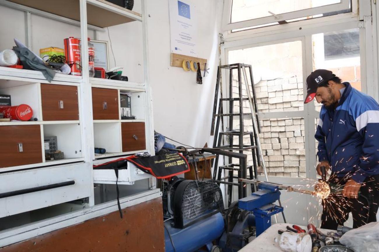 A man in Kosovo shapes metal in a workshop.