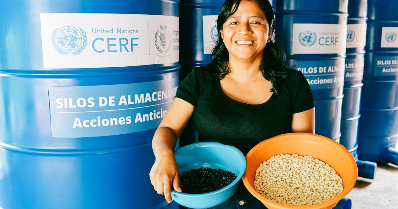 A woman in Guatemala holds two bowls full of her harvests.