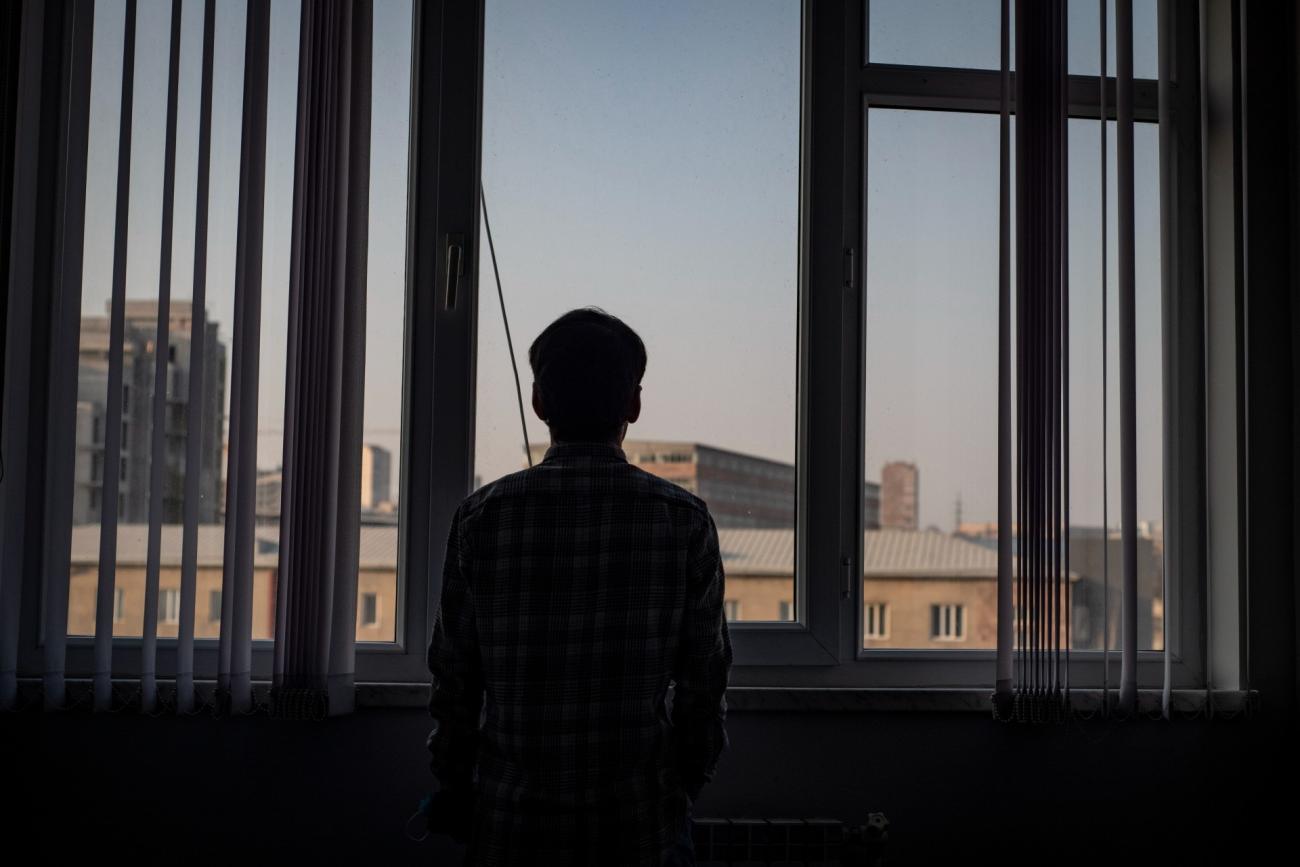 Мужчина смотрит в окно на город