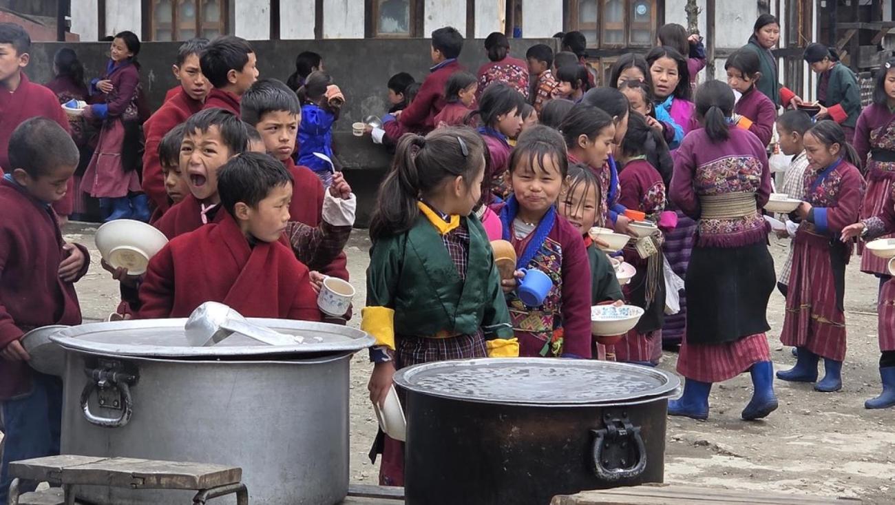 Children in Bhutan line up for their school meal.