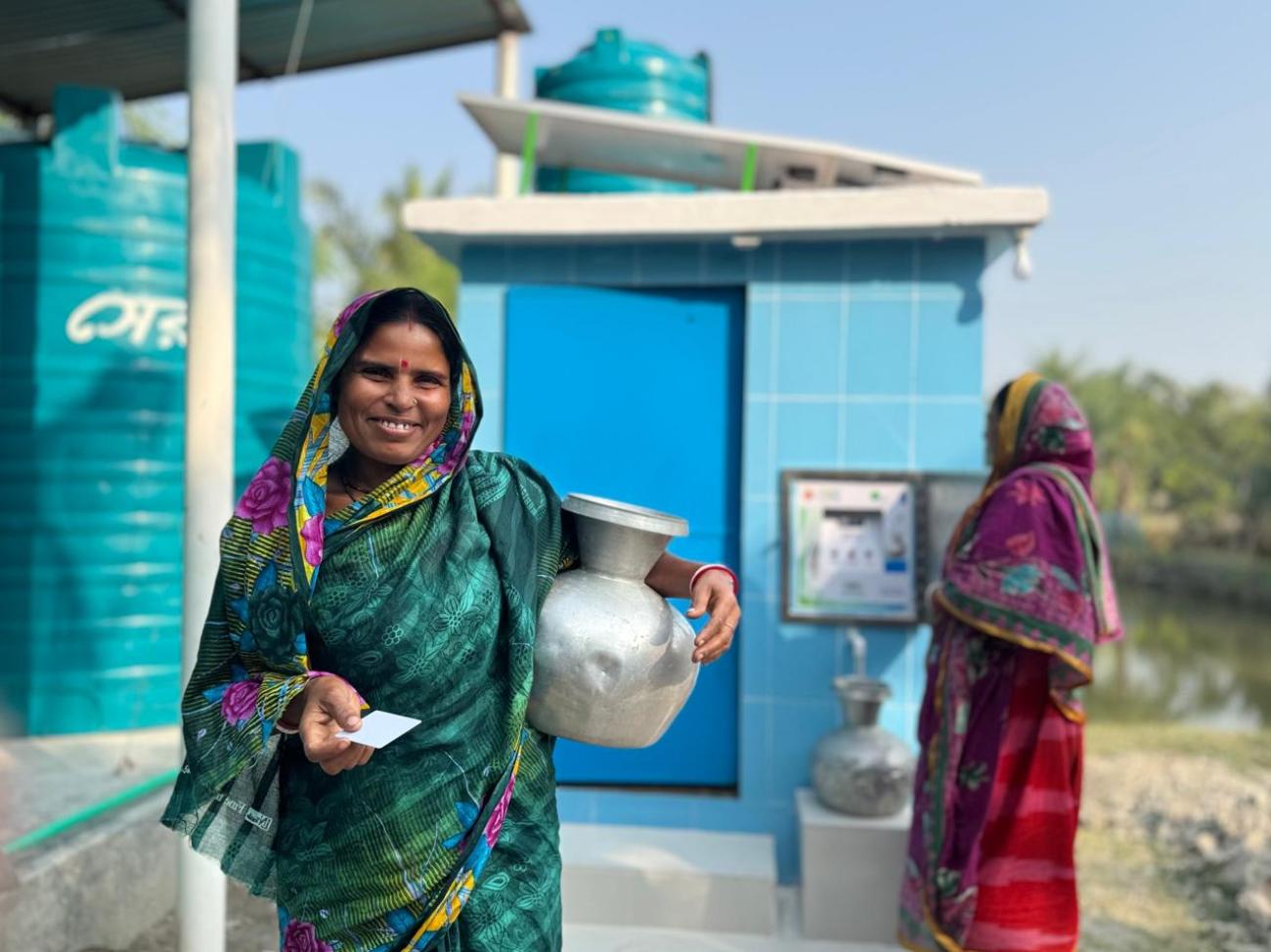 A woman in Bangladesh holds a water jug.