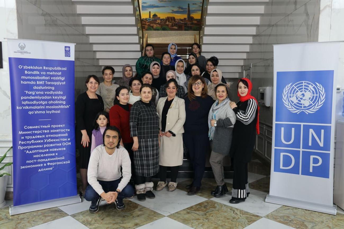 Группа людей позирует для совместной фотографии рядом с баннерами ПРООН.