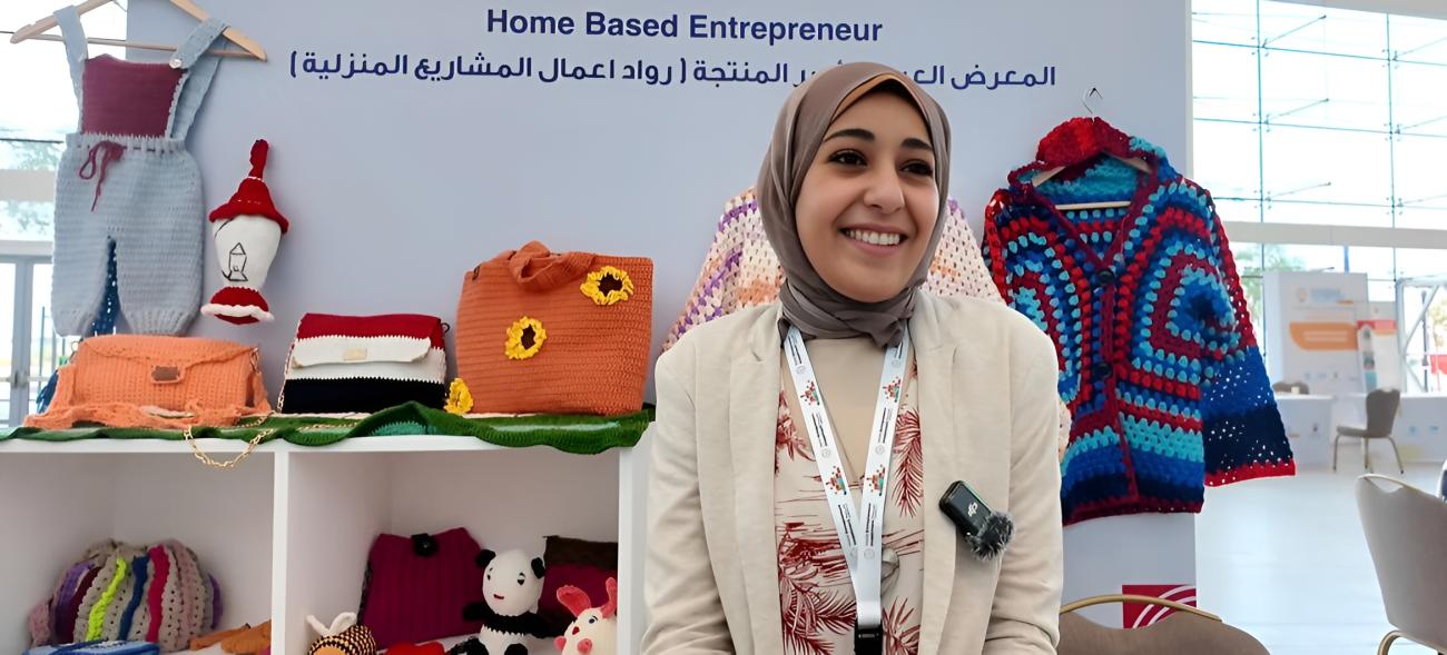 A woman at a conference in Bahrain shows her entrepreneurial work, such as bags and a top.