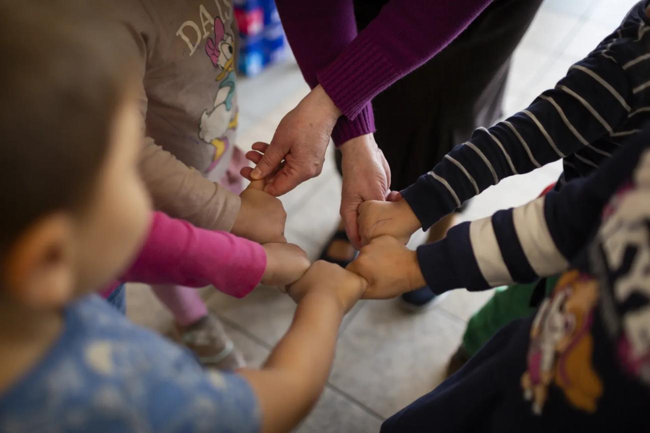 A group of kinds in Poland join fists in a circle.