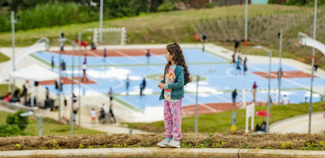 A young girl in Costa Rica stands on a hill overlooking a park.