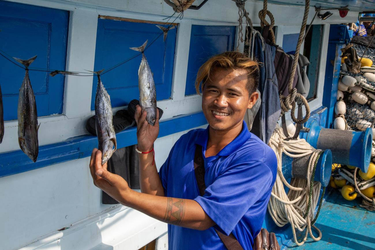 A migrant fisher in Thailand holds his catch