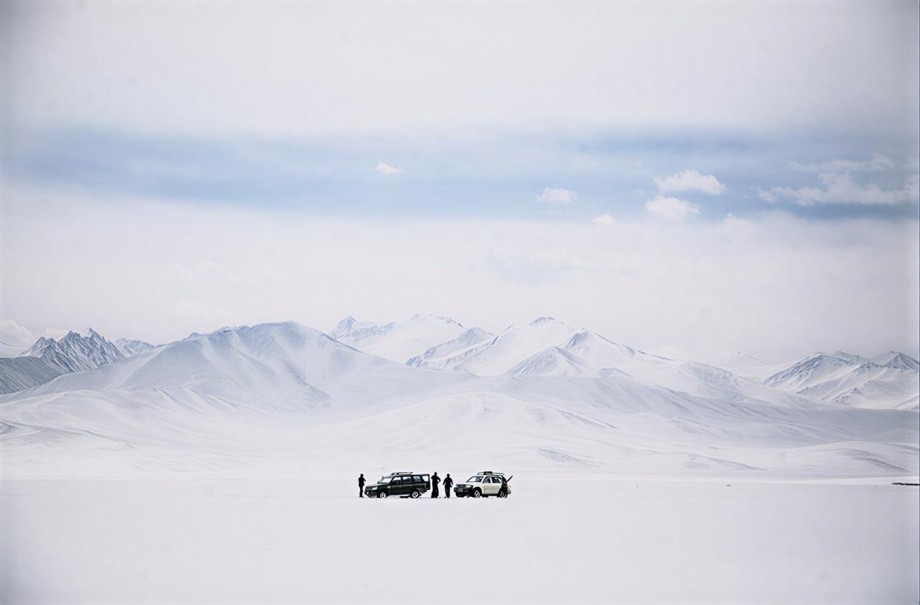 A group of people in Tajikistan in front of snowy mountains.