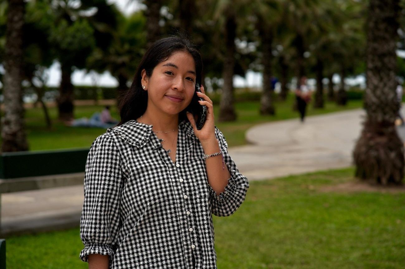 Una mujer joven sonríe mientras habla por teléfono en un parque.