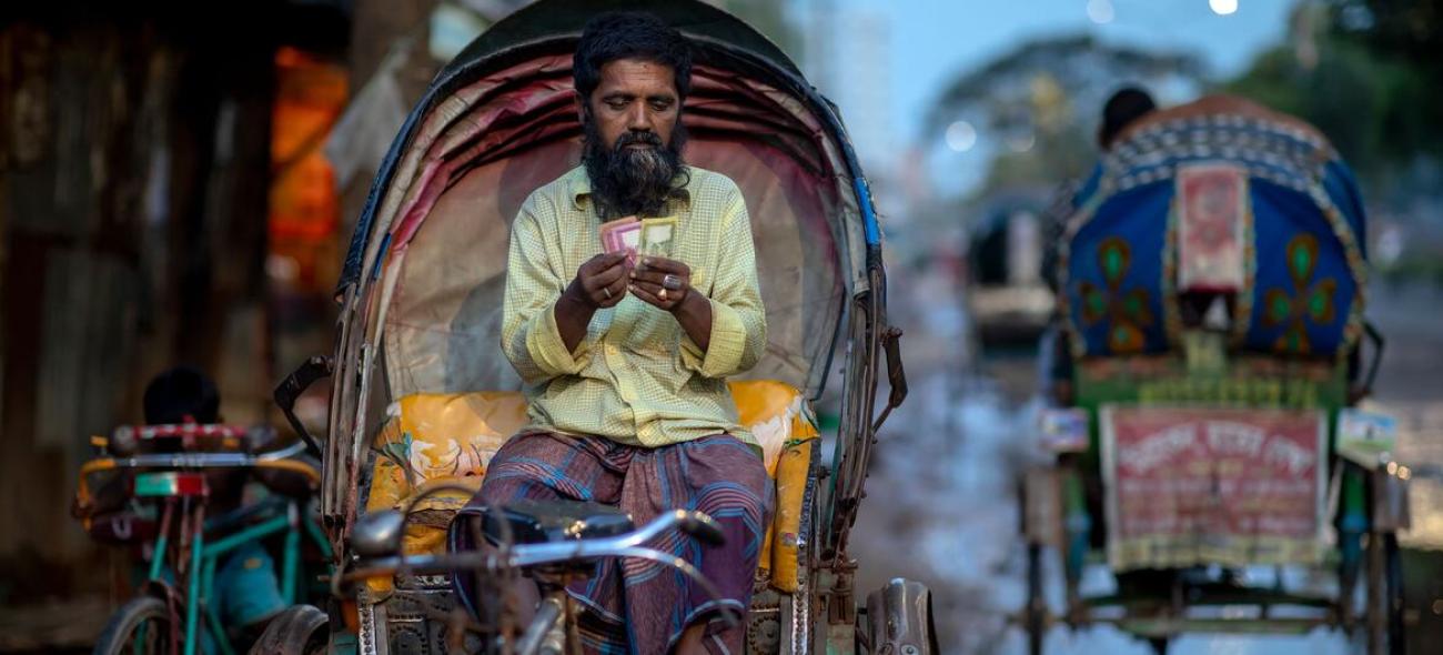 Un homme compte les gains de sa journée sur son rickshaw à Dhaka, au Bangladesh.