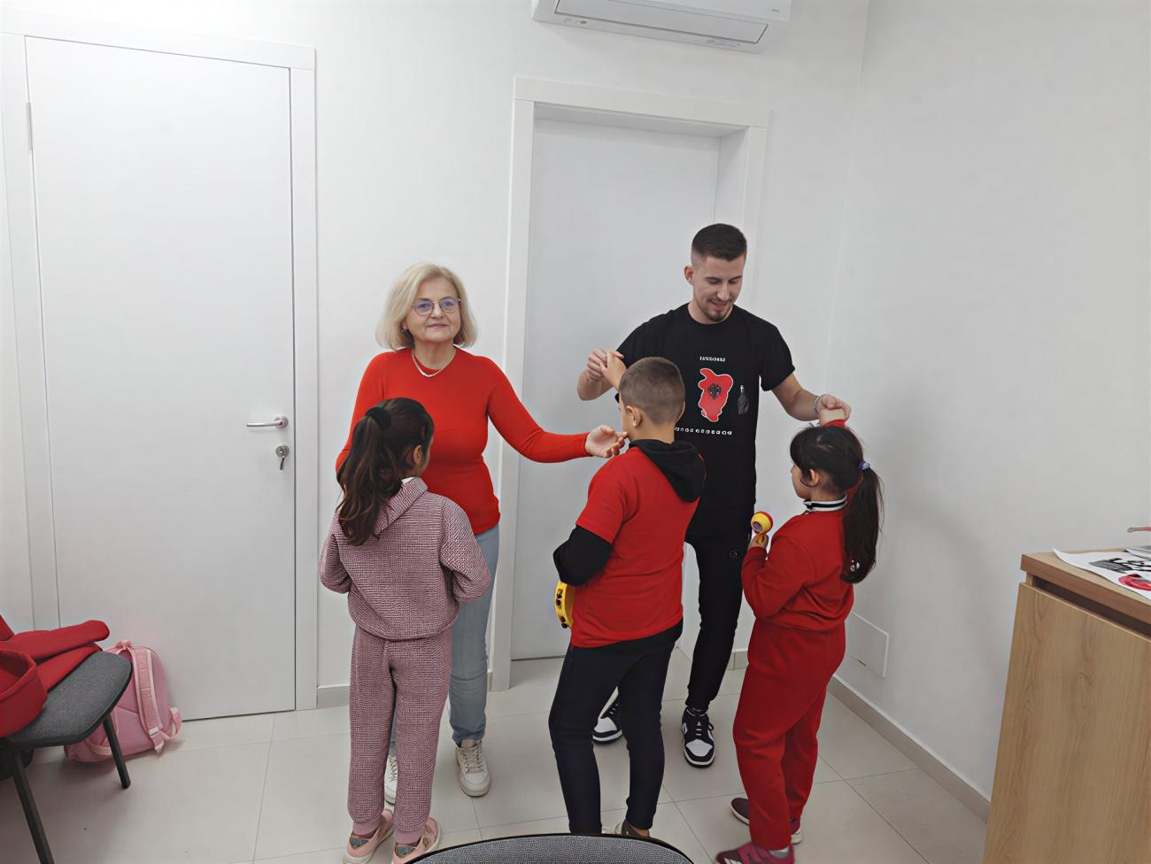 Two adults interact with three children at a community centre in Albania.