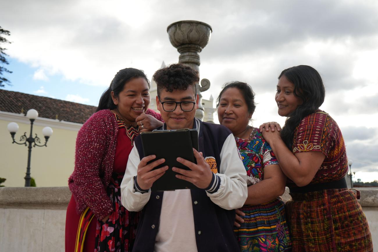 A young man and three women in Guatemala use a tablet.