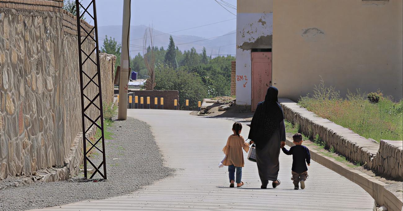 امرأة في أفغانستان تمسك بأيدي ابنها وبناتها.