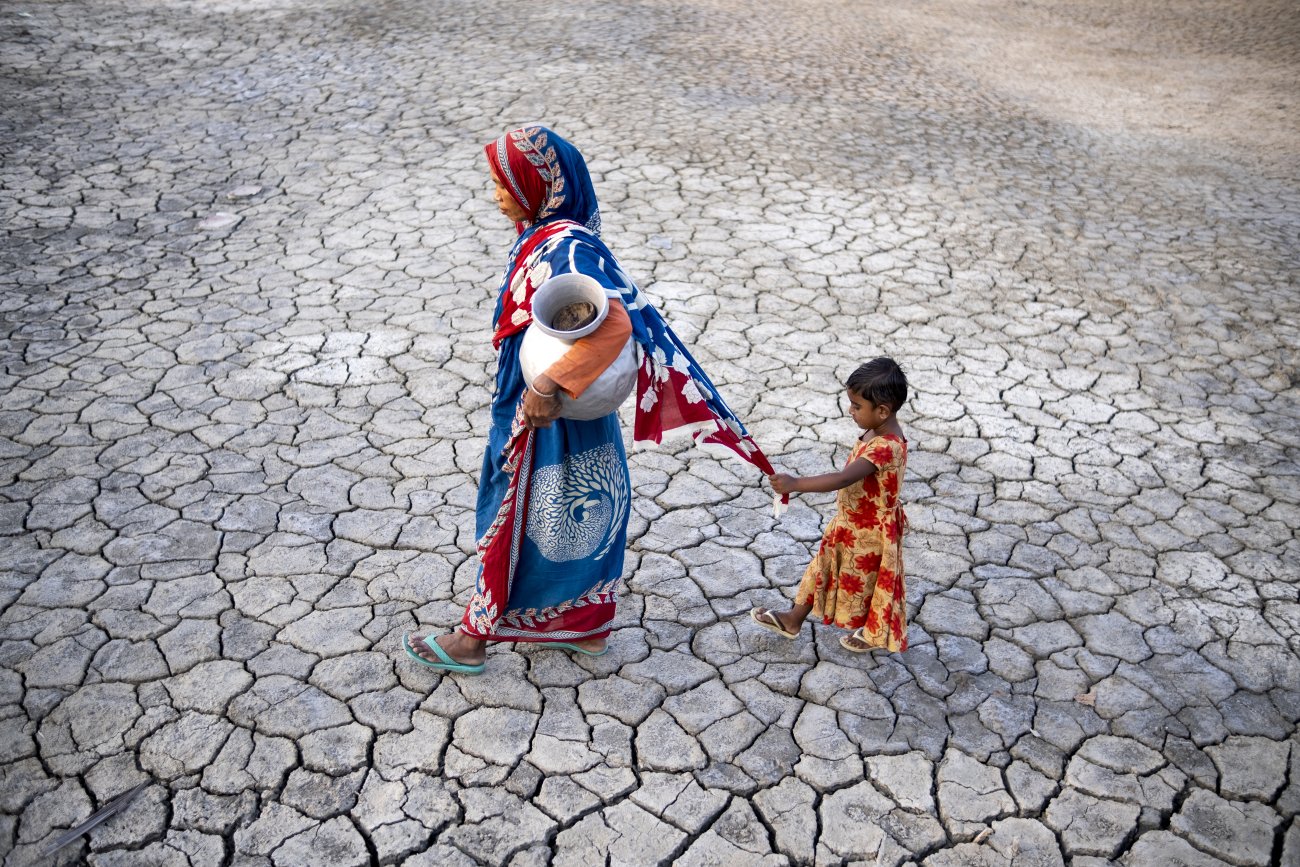 A woman in Bangladesh traverses drought-stricken land followed by her daughter.