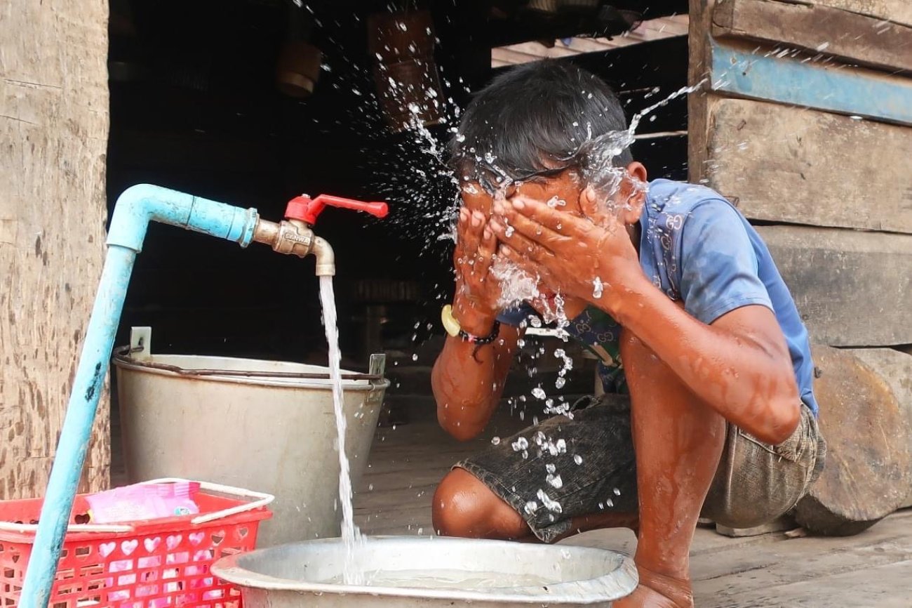 A child in Lao PDR splashes water on his face.