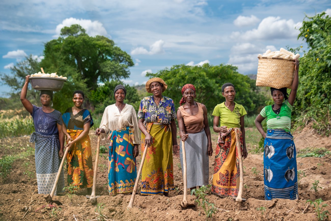 Women in Malawi happily stand in a field.