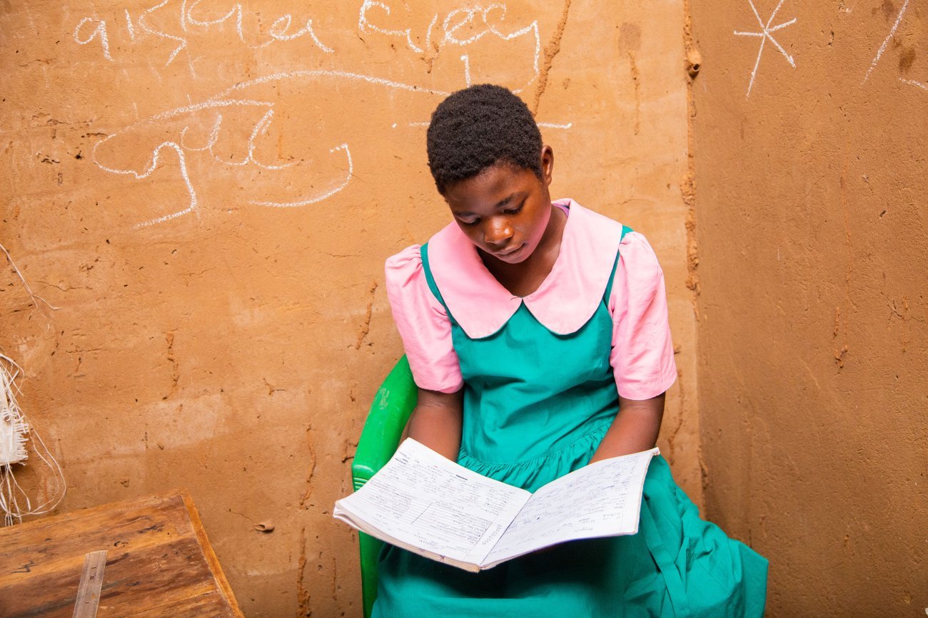 Una niña lee un libro en Malawi.