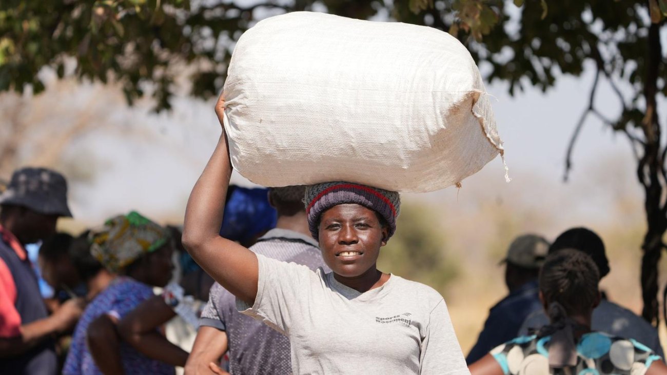 A woman in Namibia carries a bag of food on her head.