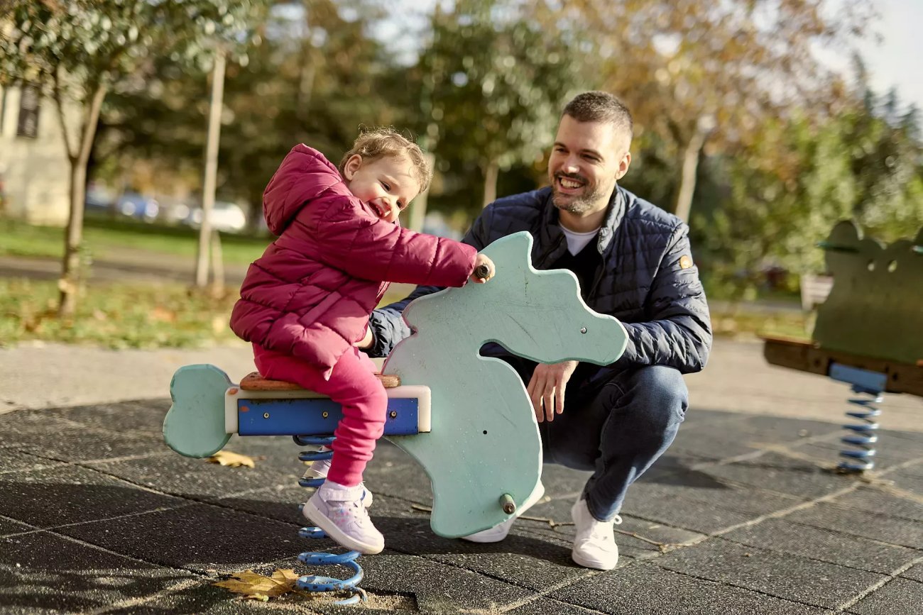 A man and his young daughter at a playground in Montenegro.