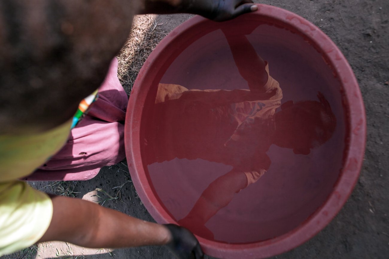A child in South Sudan sees his reflection in a bucket of water.