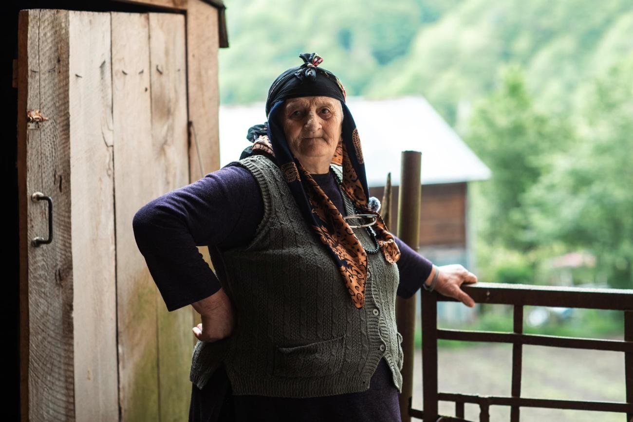 Женщина опирается на забор.