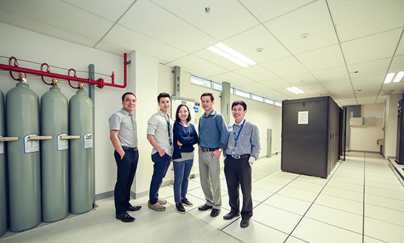 Five people stand together smiling at the camera. 