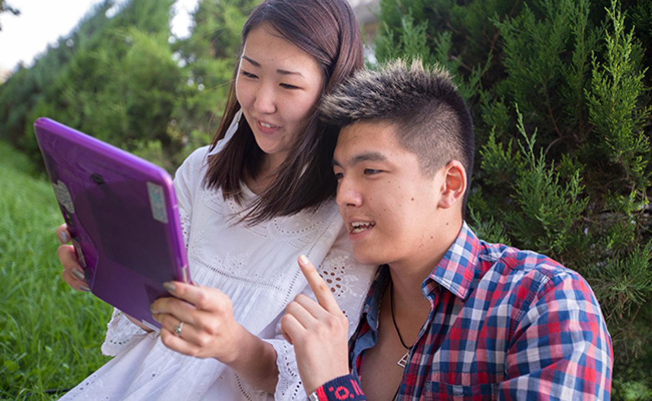 Two people look at a purple tablet. 
