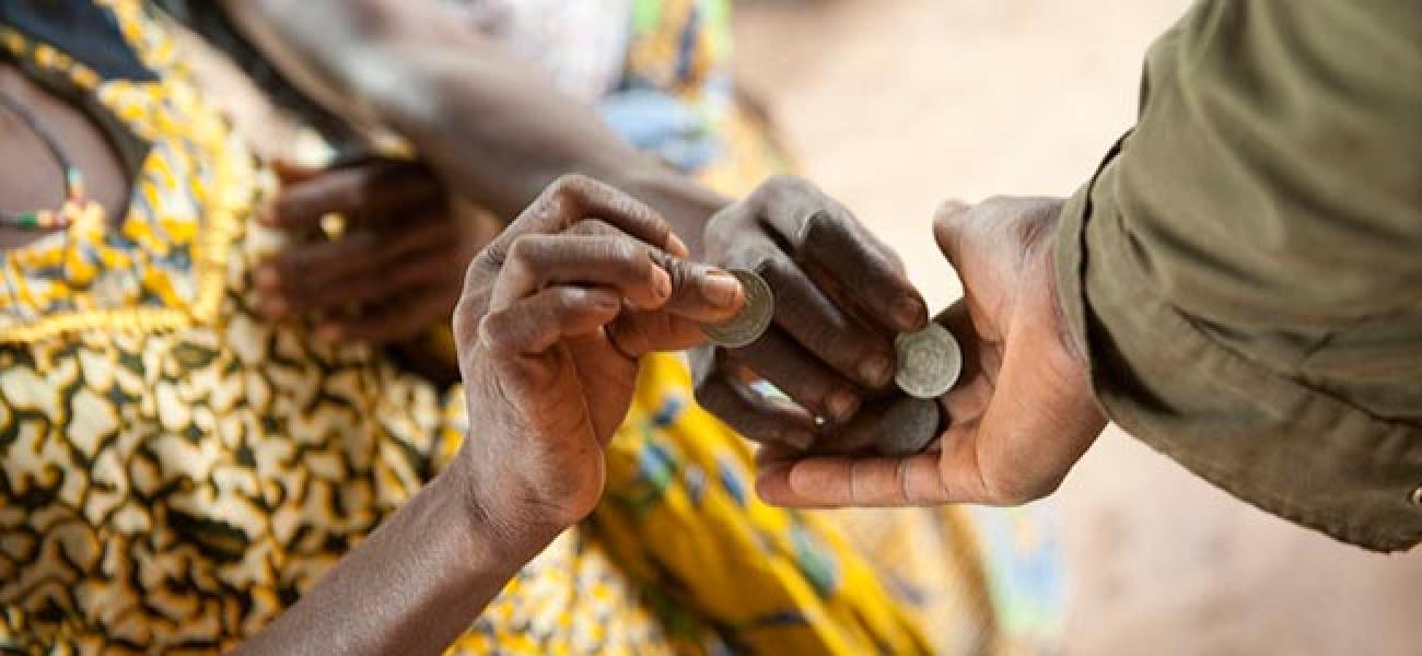 A close of image of hands exchanging coins. 