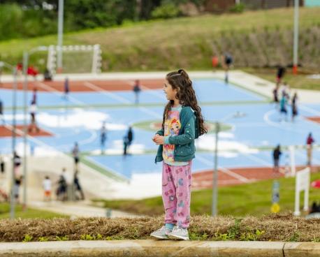 A young girl in Costa Rica stands on a hill overlooking a park.