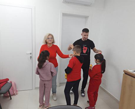 Two adults interact with three children at a community centre in Albania.