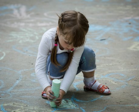 A girl in Moldova draws on the ground with chalk.