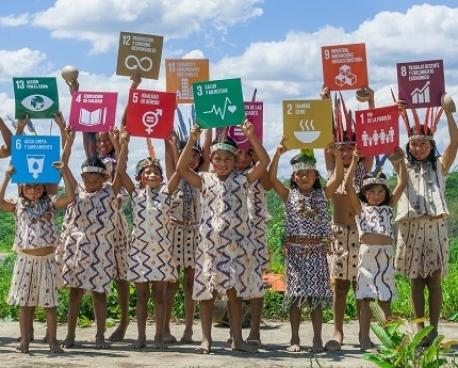 Muchos niños y niñas sostienen en alto los Objetivos de Desarrollo Sostenible.