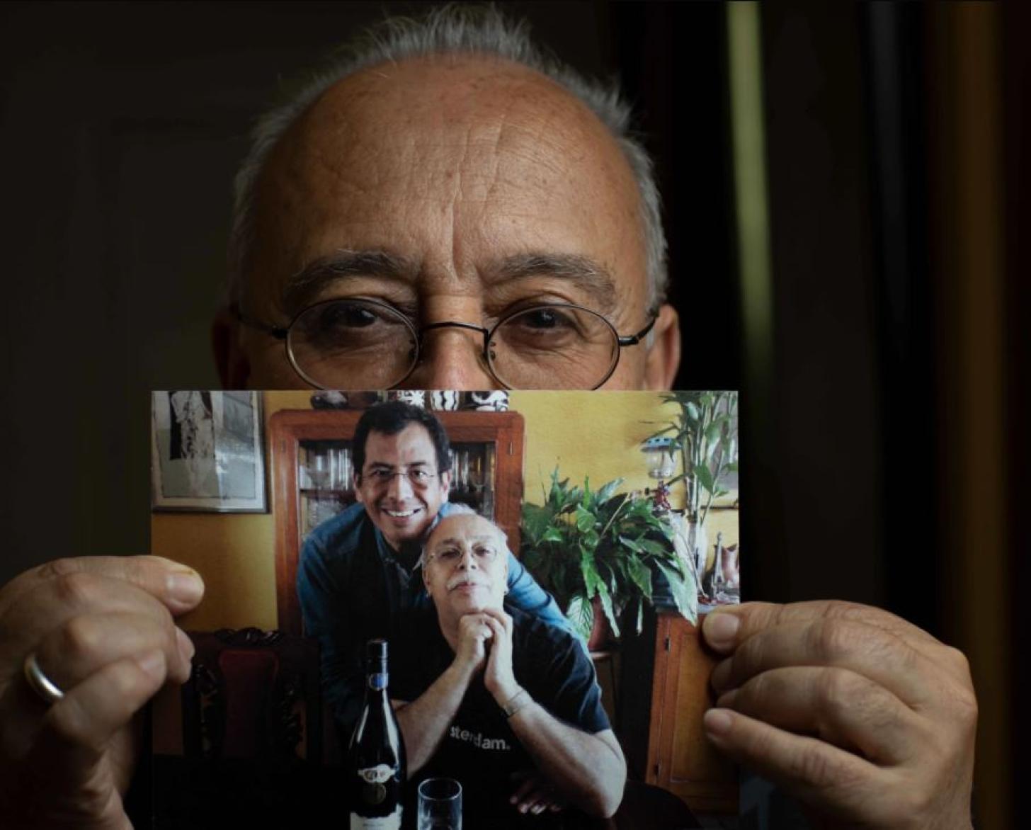 Manolo holds a photograph showing himself and his partner Martín. 