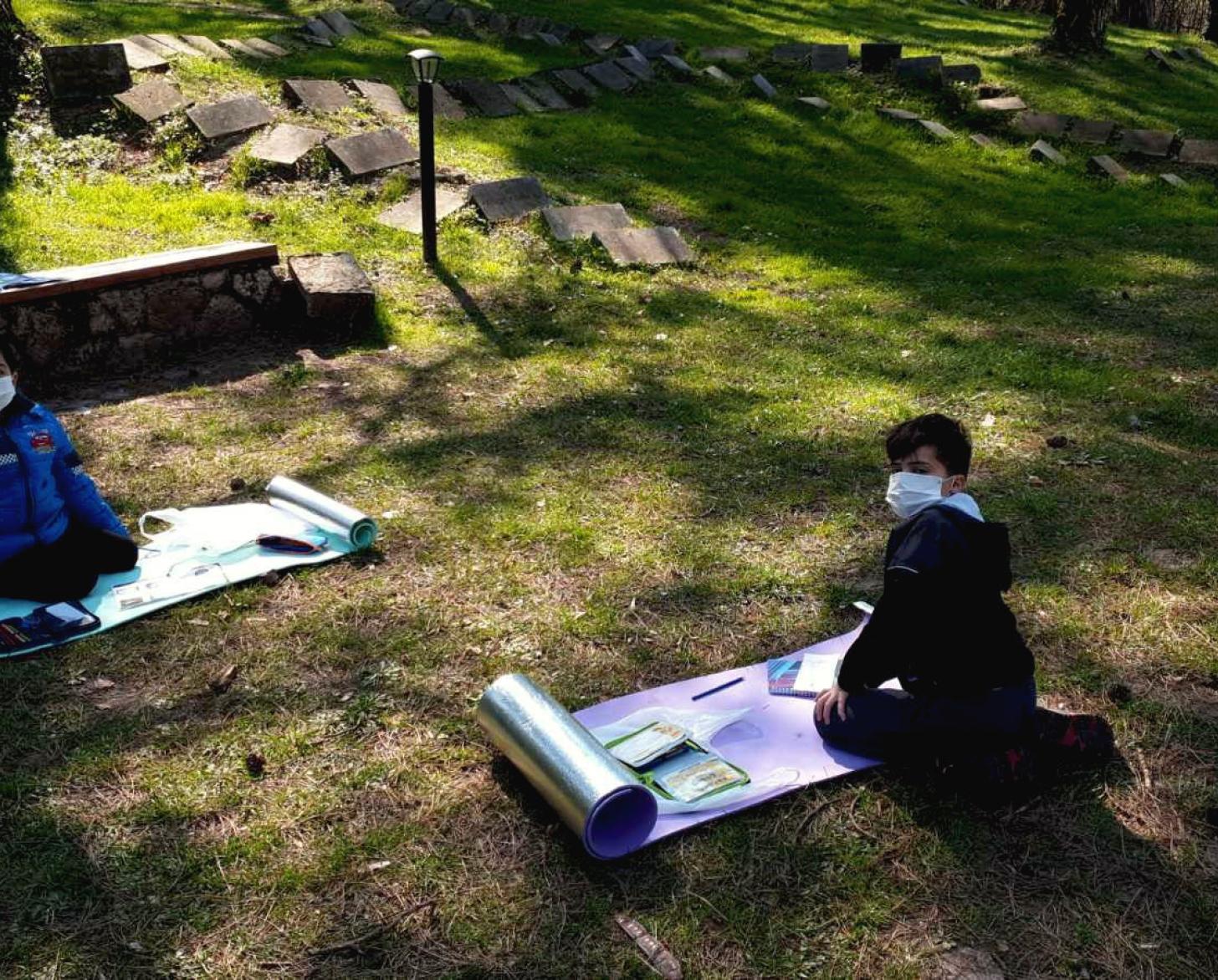 Los jóvenes estudiantes, con equipo de protección, realizan sus cursos en línea en el exterior.