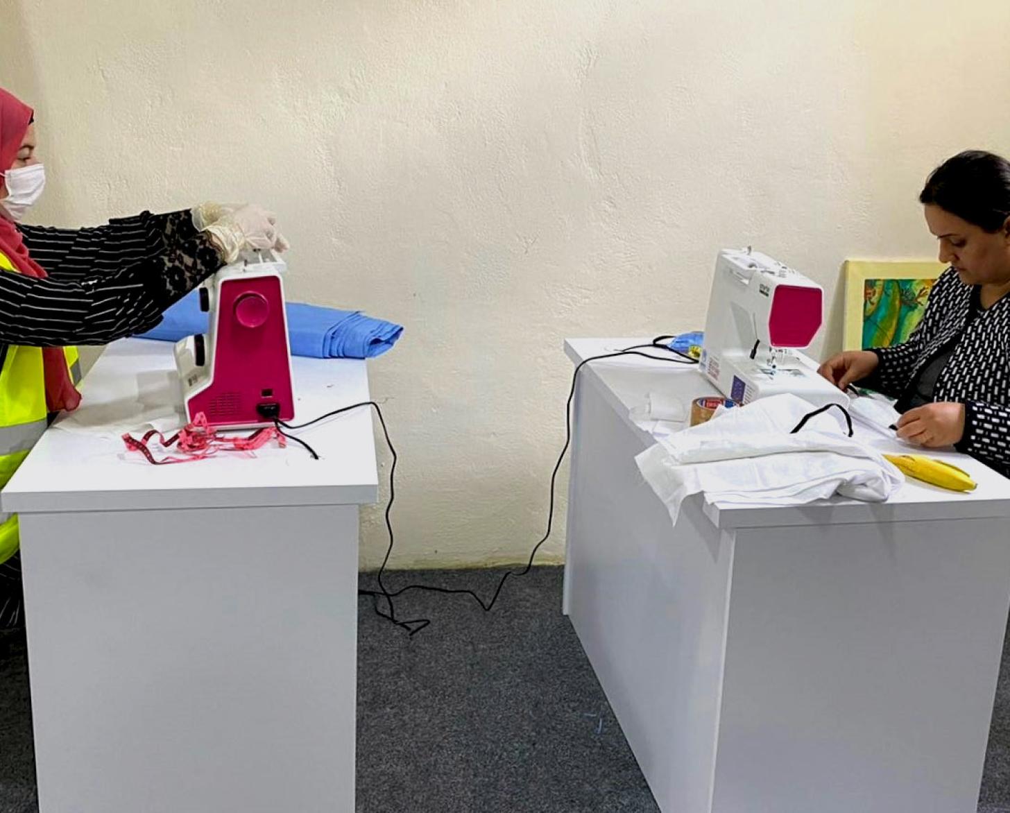 Dos mujeres cosen mascarillas de protección.