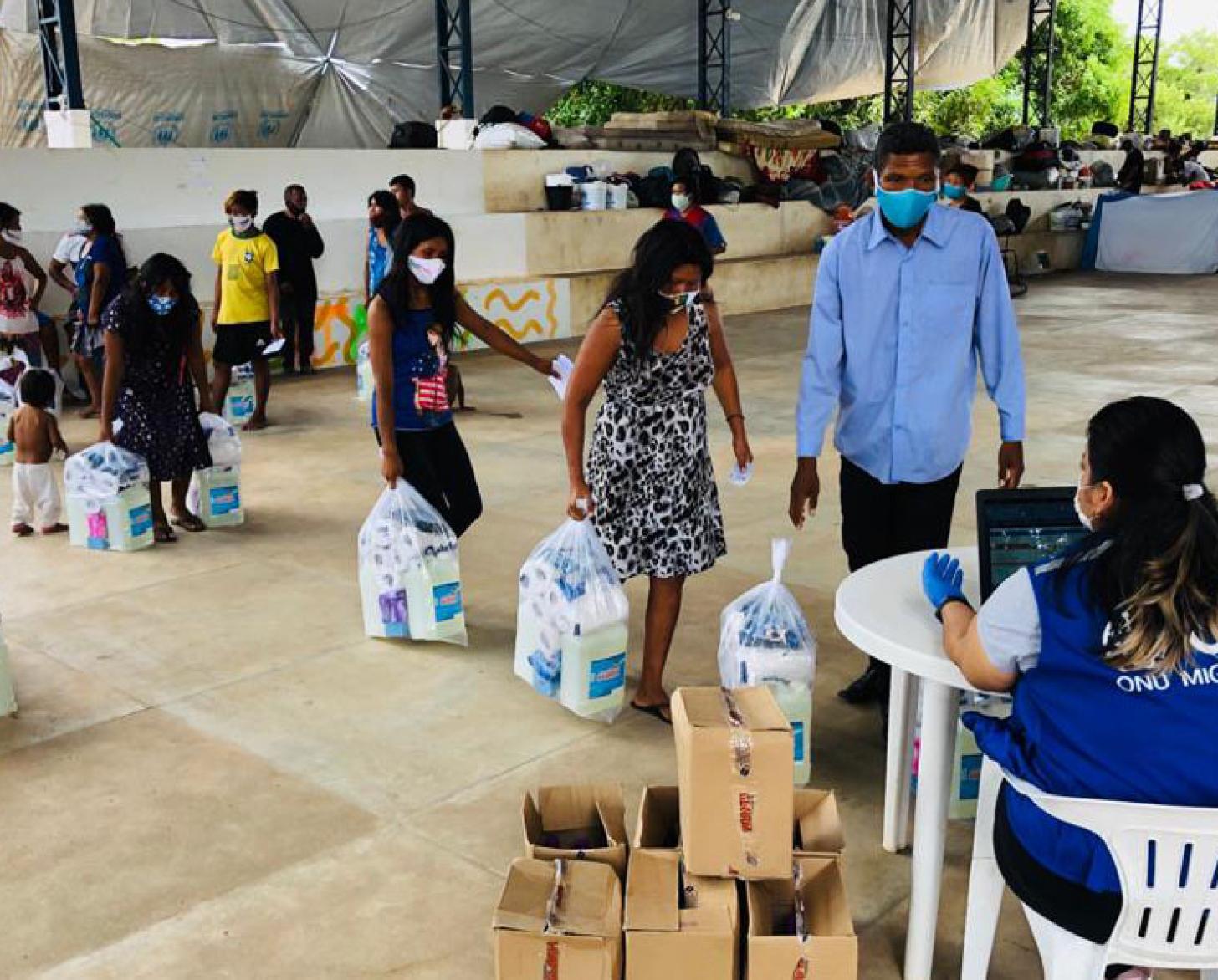 Los habitantes de un centro local obtienen suministros esenciales proporcionados por la OIM.