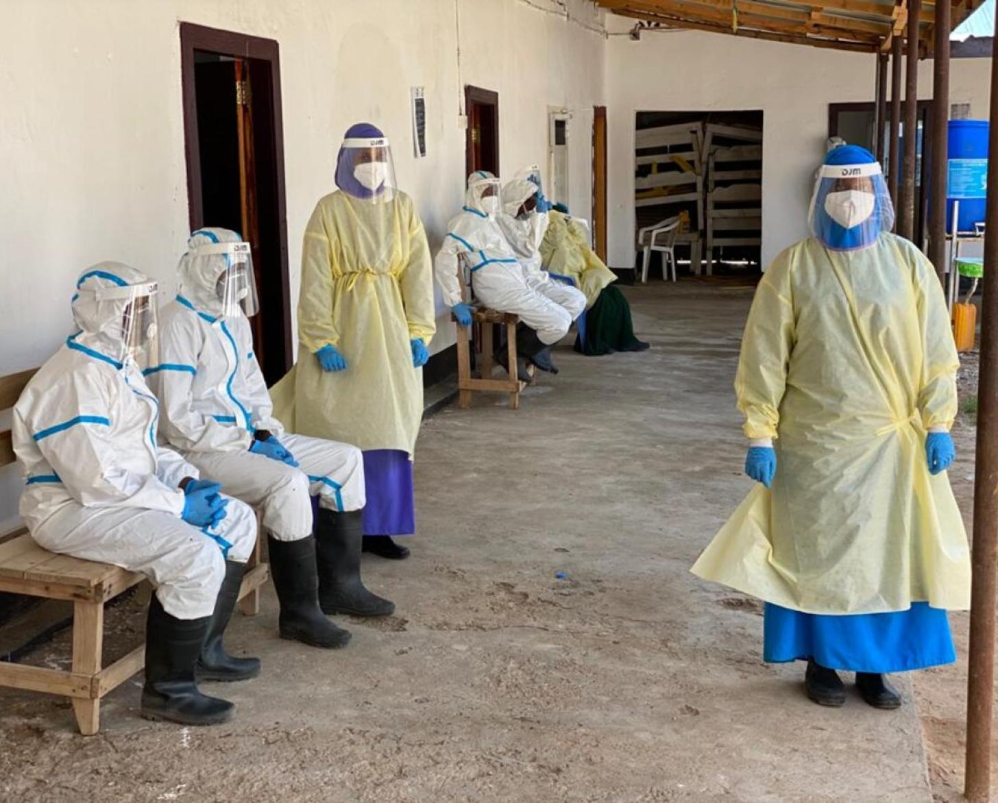 Healthcare workers at the medical facility are shown outside the facility wearing full personal protective gear.