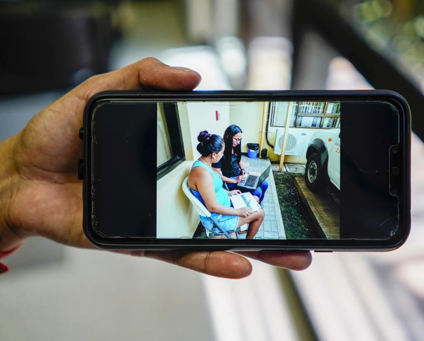 Close up of image from an iPhone of Gabriela sitting with one of her clients outside.