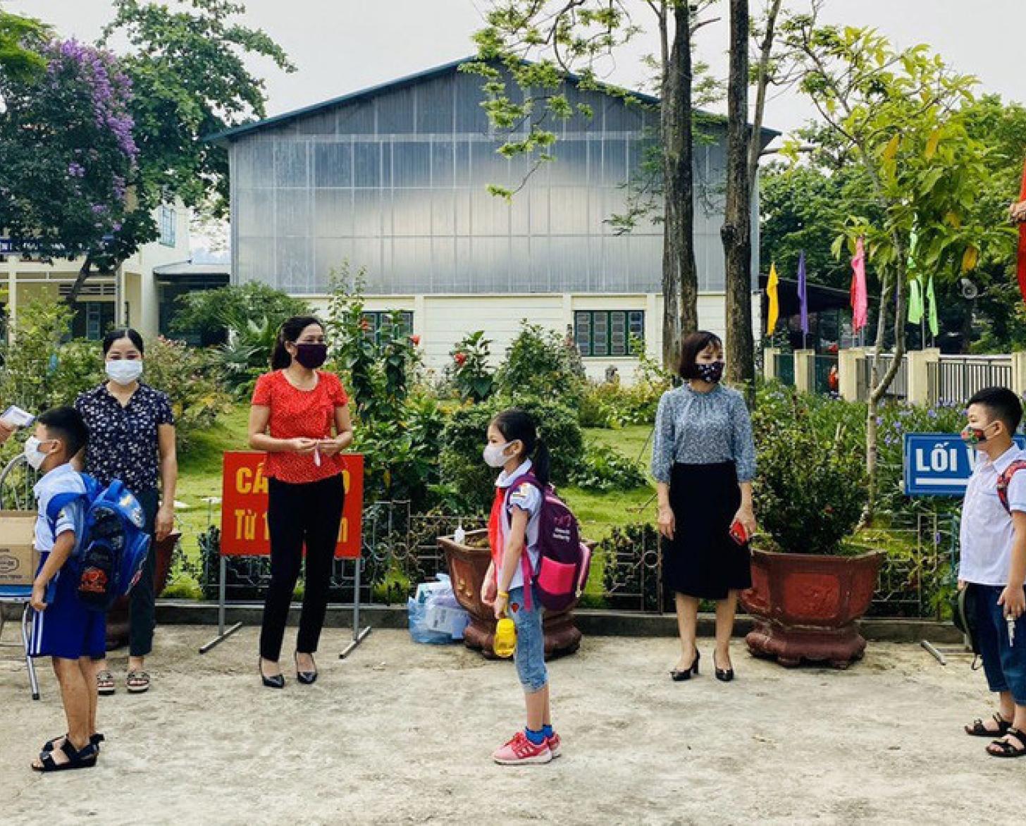 Los alumnos llevan mascarillas protectoras cuando se registran con los profesores fuera de la escuela.