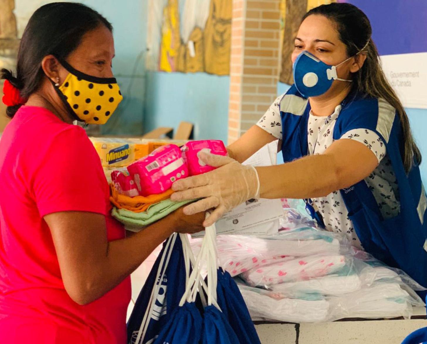 موظفة في المنظمة الدولية للهجرة تقدم المستلزمات الأساسية لامرأة من الشعوب الأصلية.