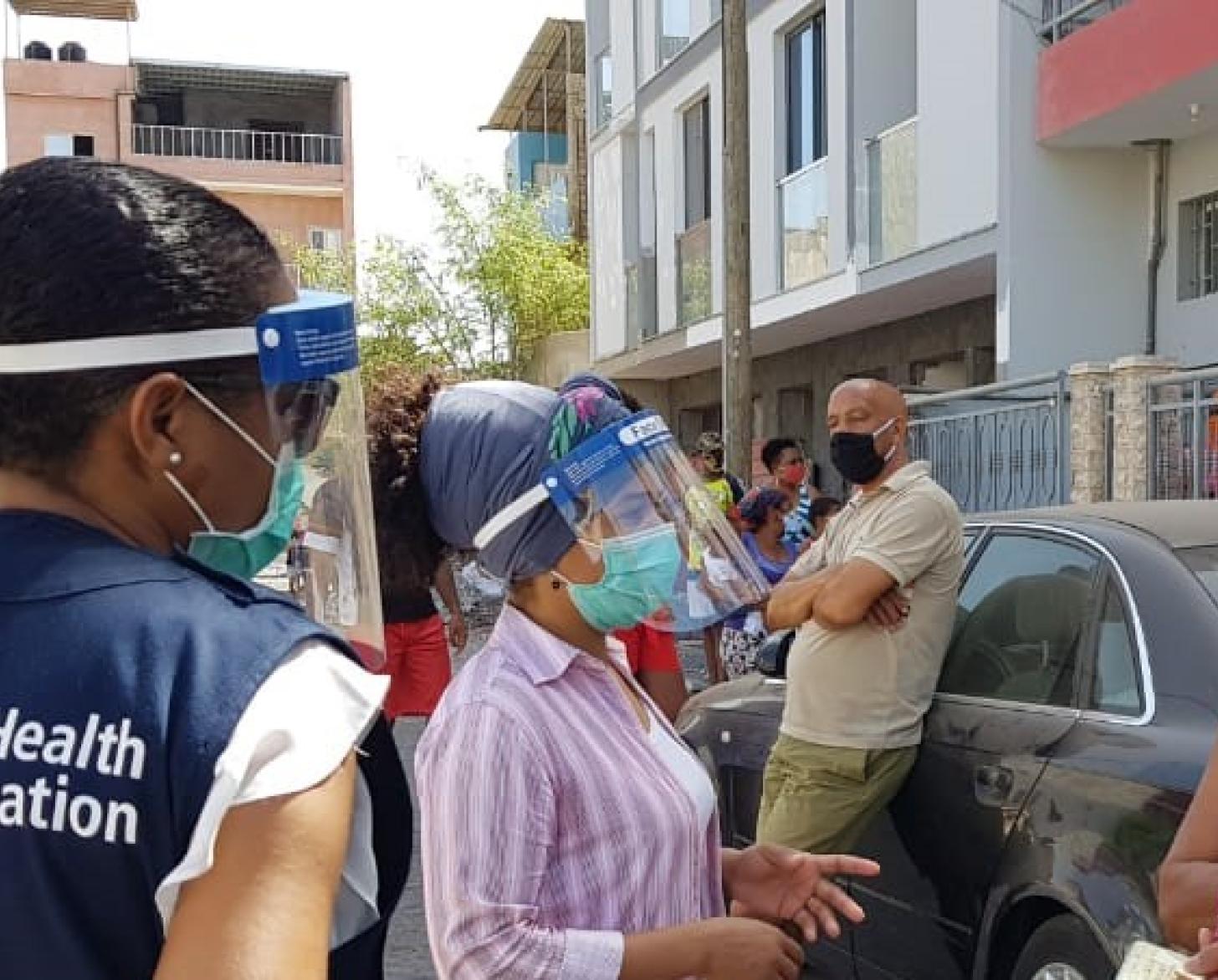World Health Organization staff member stands with two women outside a neighbourhood in Cabo Verde.