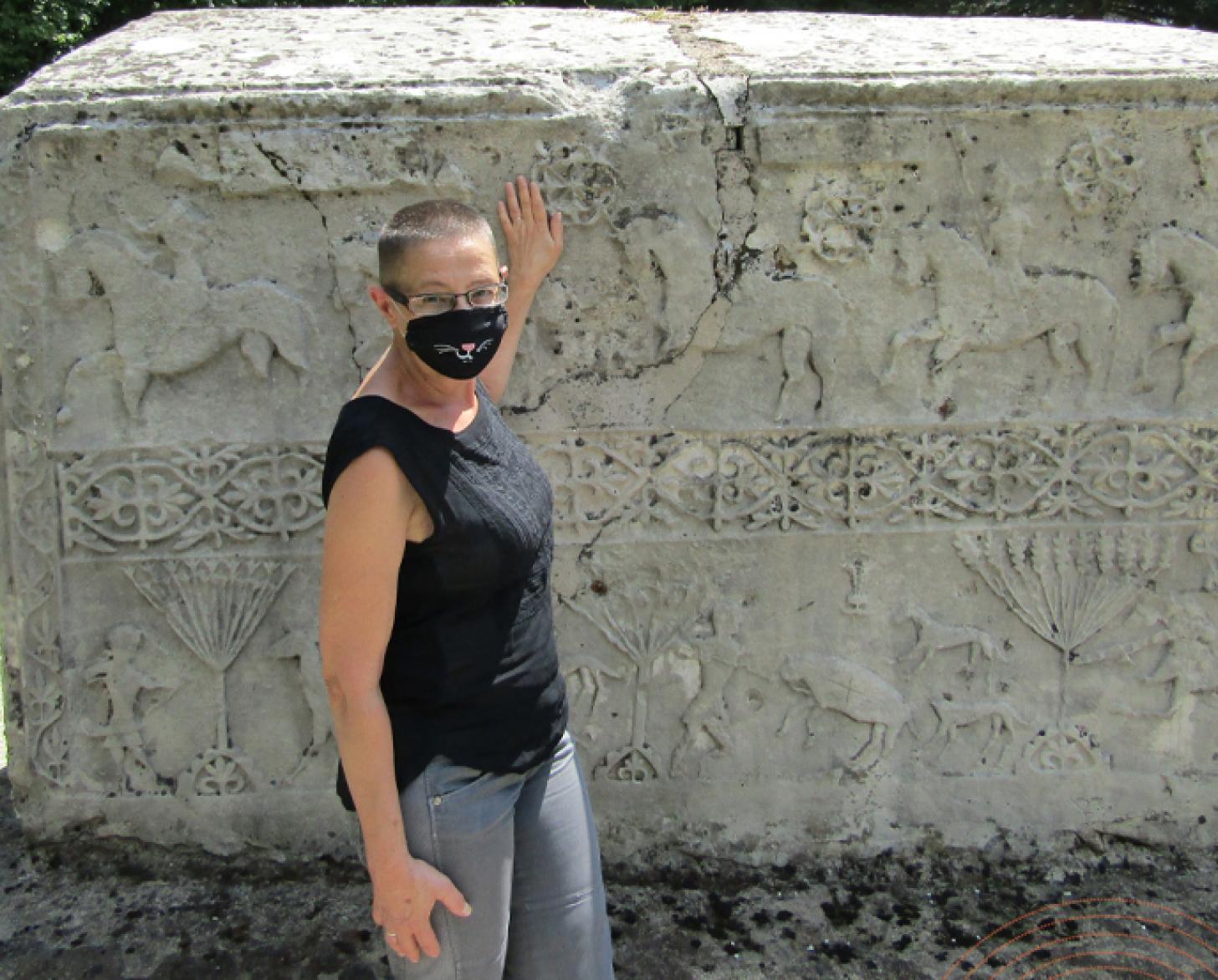Andrea Dautovic se encuentra junto a una gran escultura encajonada en el Museo Nacional de Bosnia y Herzegovina con una mascarilla facial.