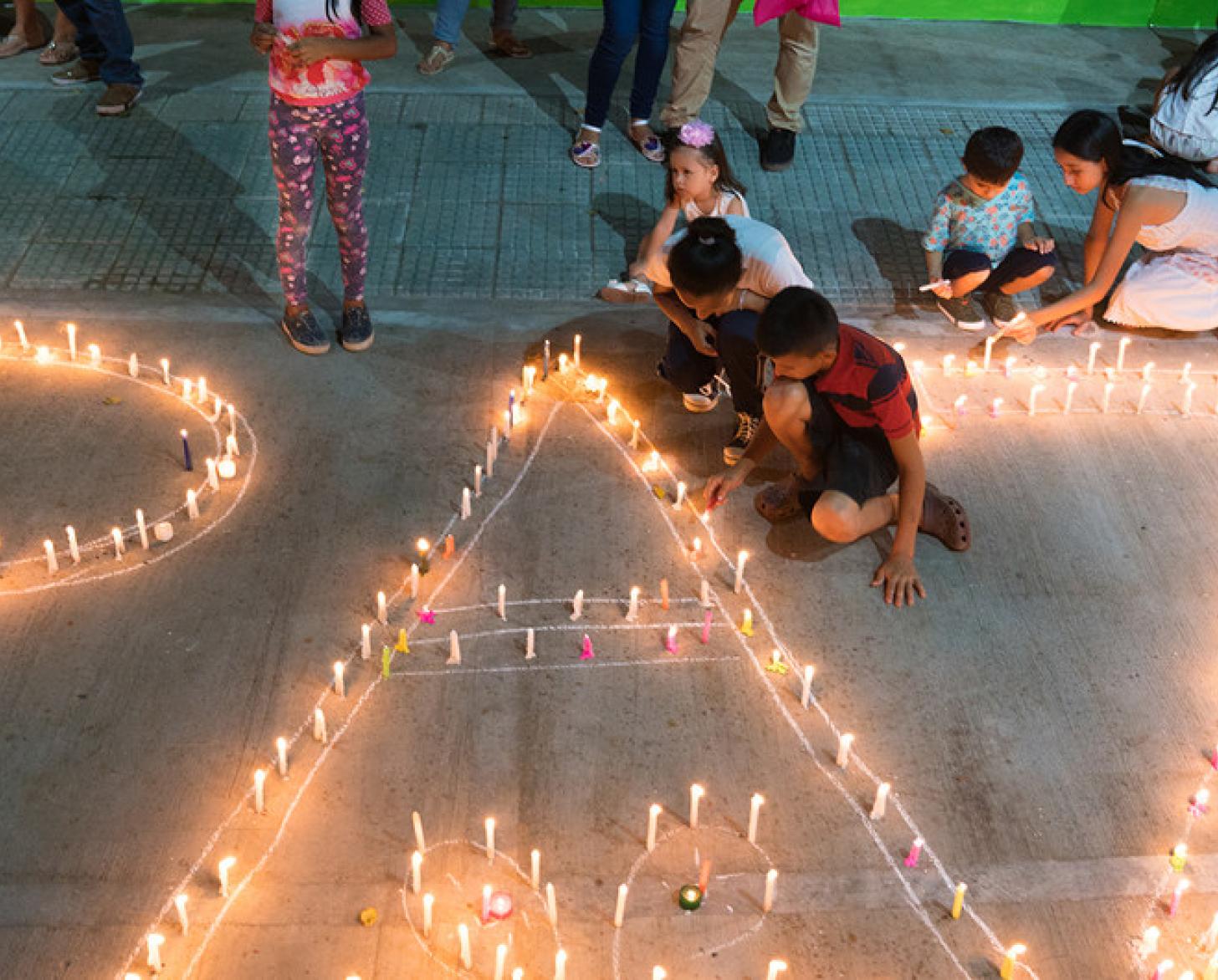 Mujeres y niños encienden velas que forman la palabra paz, en Mocoa, Colombia.