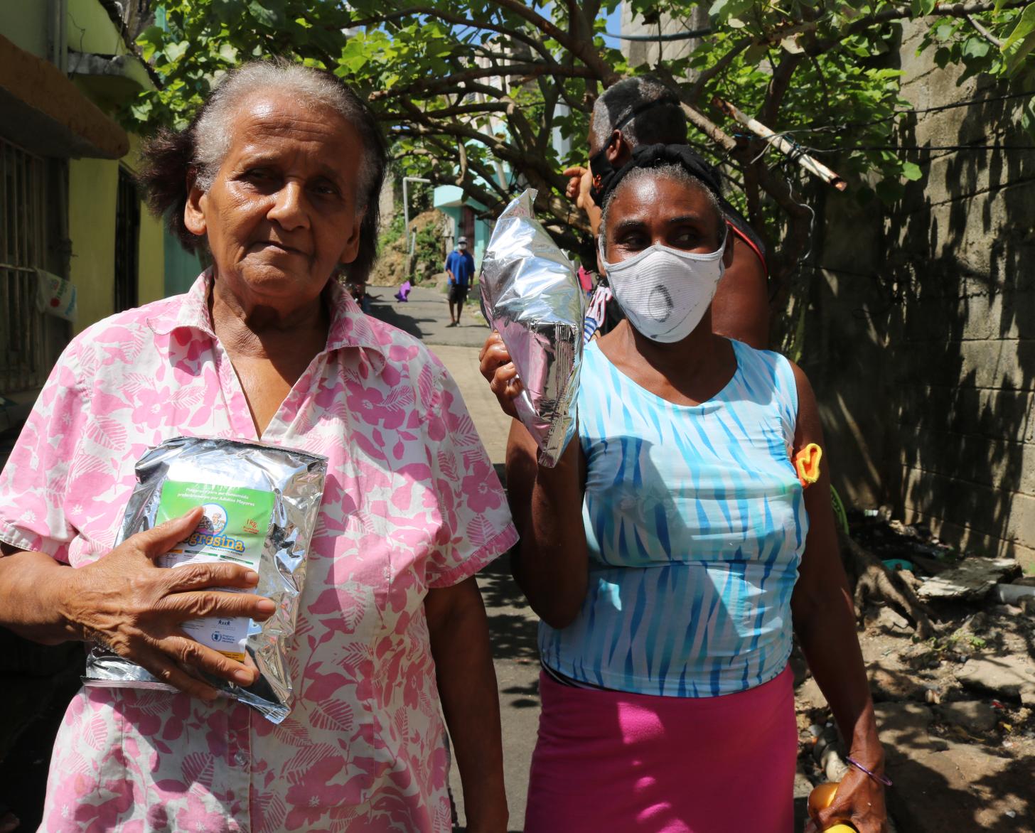 امرأتان تحملان الإمدادات الغذائية المقدمة من برنامج الغذاء العالمي.